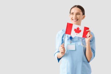 Hafif arka planda Kanada bayrağı taşıyan kadın doktor.