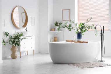 Küvet, çekmeceler ve vazolar. Banyonun iç tarafında yasemin çiçekleri açan vazolar.