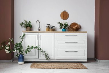 Mutfağın içindeki tezgahların üzerinde yasemin çiçekleri açan vazolar ve ürünlerle dolu kavanozlar.