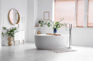 Küvet, çekmeceler ve vazolar. Banyonun iç tarafında yasemin çiçekleri açan vazolar.