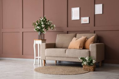 Rahat bir kanepe, masa ve çiçek açan yasemin çiçekleri oturma odasının içinde.