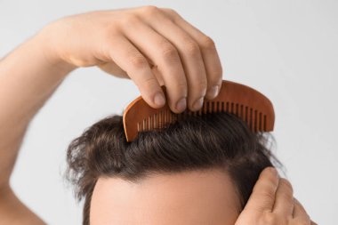 Açık arkaplanda saç tarayan adam, yakın plan.