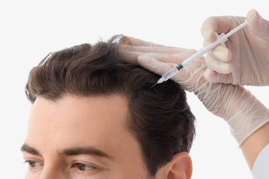 Doktor beyaz arka planda saç büyümesi için iğne yapıyor, yakın plan.