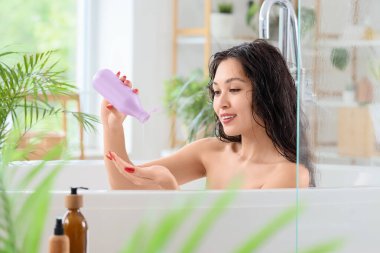 Saçlarını banyoda yıkayan, şampuanlı güzel bir Asyalı kadın.