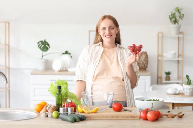 Kiraz domatesli hamile bir kadın mutfakta sebze salatası hazırlıyor.