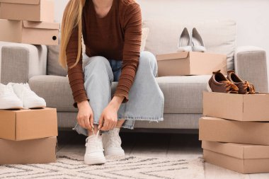 Evde koltukta oturan ayakkabılı kadın.