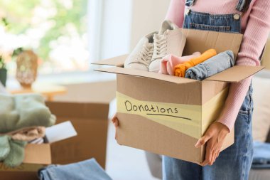 Genç bir kadın bağış için giysileriyle birlikte kutusunu tutuyor, yakın plan.