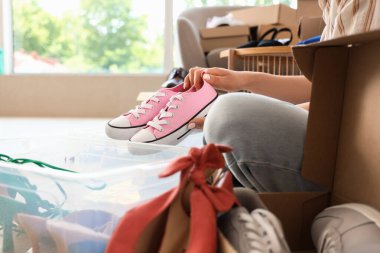 Evde spor ayakkabılarını konteynıra koyan genç bir kadın.