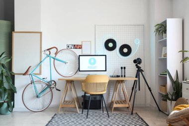 Işık podcaster stüdyosunun içinde iş yeri, vinil diskler ve bisiklet var.