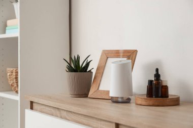 Oturma odasındaki rafta gerekli yağlar ve çerçeveli hava nemlendirici.