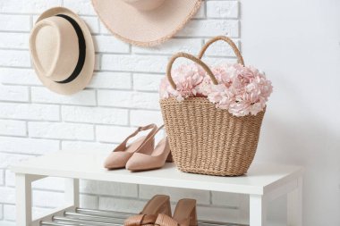 Koridordaki bankta pembe ortanca çiçekli çanta.