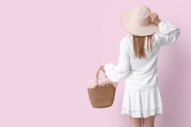 Kırmızı çiçekli kadın hasır çantada pembe arka planda, arka planda