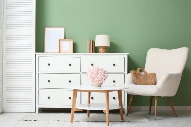 Oturma odasının içinde masa ve koltukta ortanca çiçekleri var.