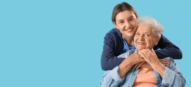 Hemşire mavi arka planda yaşlı kadına sarılıyor. Mesaj için yeri var.