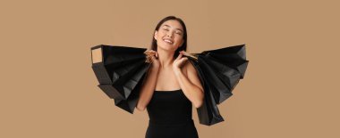 Kahverengi arka planda alışveriş torbaları olan güzel mutlu Asyalı kadın. Kara Cuma indirimi