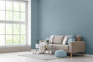 Gri kanepe, masa ve puf ile aydınlık oturma odasının içi