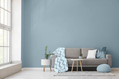 Gri kanepe, masa ve puf ile aydınlık oturma odasının içi