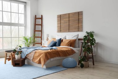 Büyük yataklı, masalı ve bitkilerli rahat bir yatak odası.