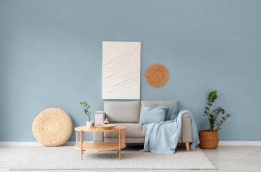 Oturma odasının iç tarafındaki beyaz duvarın yanındaki kanepe ve ahşap sehpa.