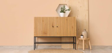 Odanın içinde ahşap klozet, tabure ve bitki var.