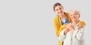 Hemşire, açık arkaplanda yaşlı kadına sarılıyor. Mesaj için yeri var.