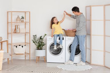 Genç baba ve kızı banyoda birbirlerine beşlik çakıyorlar.