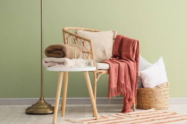 Ev dekorasyonu ve yeşil duvarın yanındaki sehpanın üzerinde duran şık sonbahar kıyafetleri yığını.