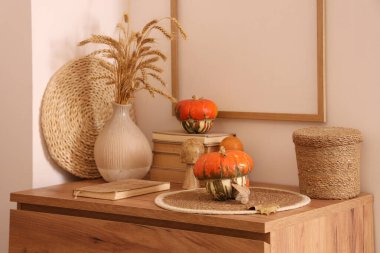 Kitaplar ve vazolar, sonbaharda oturma odasının iç kısımlarında çekmecelerin üzerinde otlar olacak.