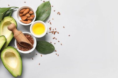 Olgun avokado, yağlı kase, badem ve gri arka planda keten tohumu karışımı.