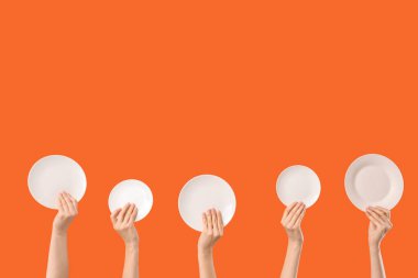 Turuncu arka planda temiz beyaz plakalı kadın elleri.