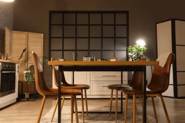 Mutfağın içinde tezgahlar, yemek masası ve akşamları parlayan lamba.