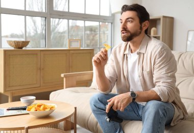 Adam evde video oyunu oynarken lezzetli nacho yiyor.