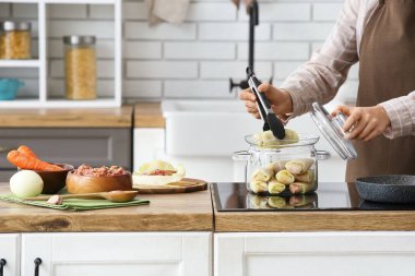 Kadın mutfaktaki fırında pişirme kabından lahana sarması alıyor, yakın plan.