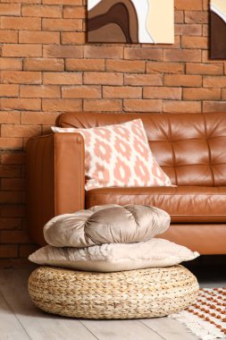 Oturma odasının içinde yastıklı rahat bir kanepe ve puf.