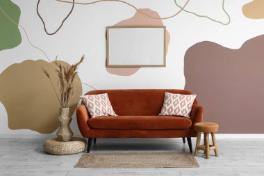 Kahverengi kanepesi, boş çerçevesi ve otları olan şık bir oturma odası.