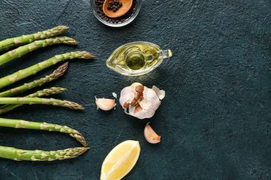 Limonlu, sarımsaklı, biberli ve koyu arkaplanlı taze yeşil kuşkonmaz.