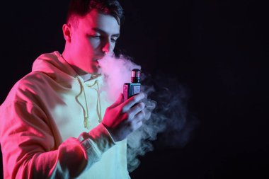 Genç adam arka planda elektronik sigara içiyor.