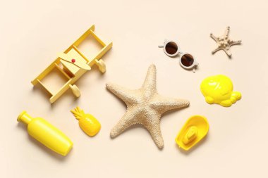Deniz yıldızları, güneş kremi, güneş gözlüğü ve bej arkaplanda kumsal kalıpları olan kompozisyon