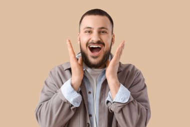 Bej arka planda güzel gülüşü olan genç adam.