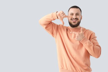 Genç adam gülüşünü açık arkaplanda gösteriyor.