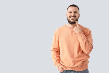 Genç adam arka plandaki gülüşüne işaret ediyor.