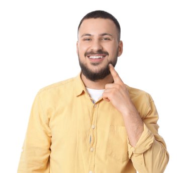 Genç adam beyaz arka plandaki gülüşüne işaret ediyor.