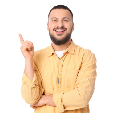 Güzel gülüşü olan genç adam beyaz arka plandaki bir şeyi işaret ediyor.