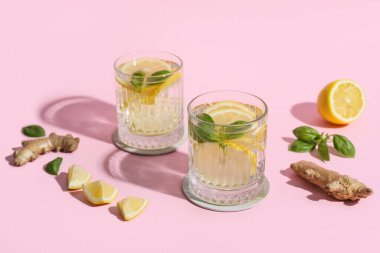 Zencefil ve fesleğenle doldurulmuş taze limonlu su bardakları.