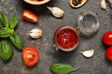 Lezzetli ketçap kavanozu ve koyu arkaplanda farklı malzemeler.