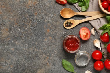 Lezzetli ketçap kavanozu ve koyu arkaplanda farklı malzemeler.