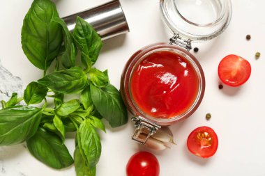 Fesleğen yapraklı ketçap kavanozu ve beyaz arka planda biber.