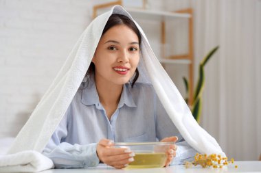 Havlulu genç Asyalı kadın yatak odasında buhar soluyor.