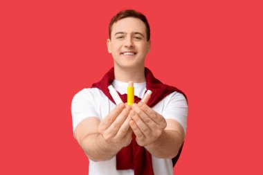 Kırmızı arka planda dudak kremi olan yakışıklı bir genç.