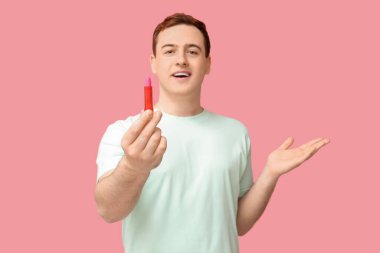 Pembe arka planda dudak merhemi olan yakışıklı bir genç.